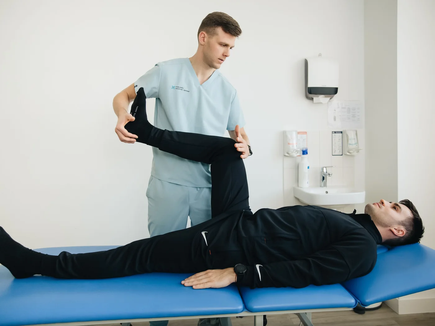 Fisioterapeuta acompanhando exercícios de reabilitação em clínica.